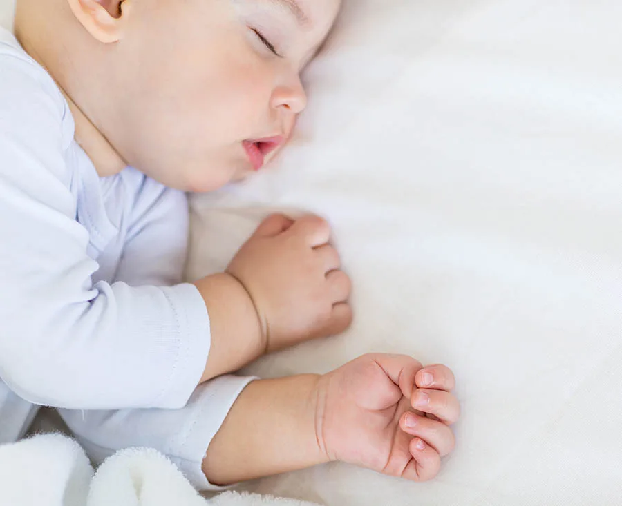 Baby ligt lekker te slapen op een kindermatras